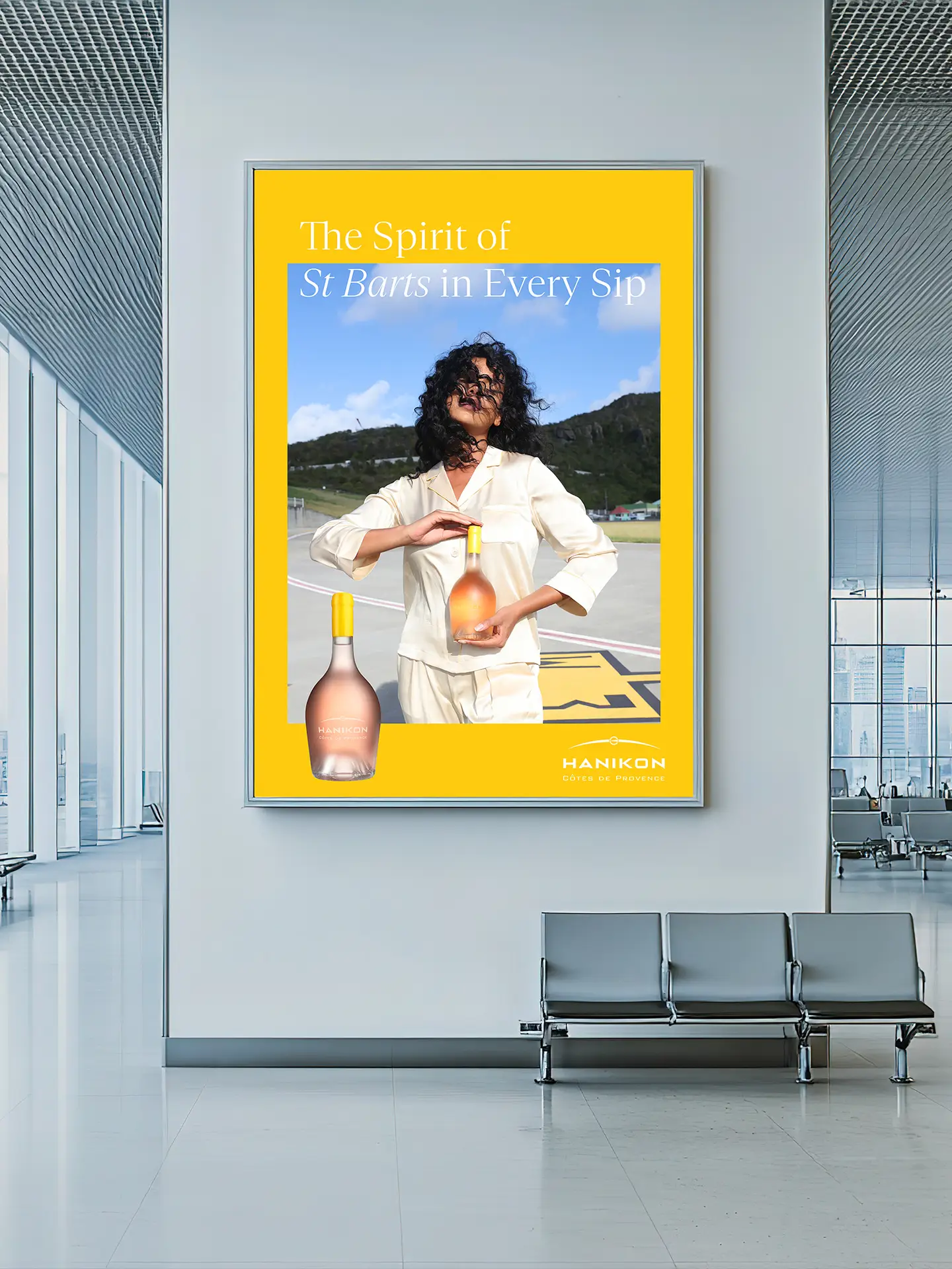Airport campaign visual created by Saltco for luxury rosé brand Hanikon, featuring a model holding a rosé bottle with the headline ‘The Spirit of St Barts in Every Sip’
