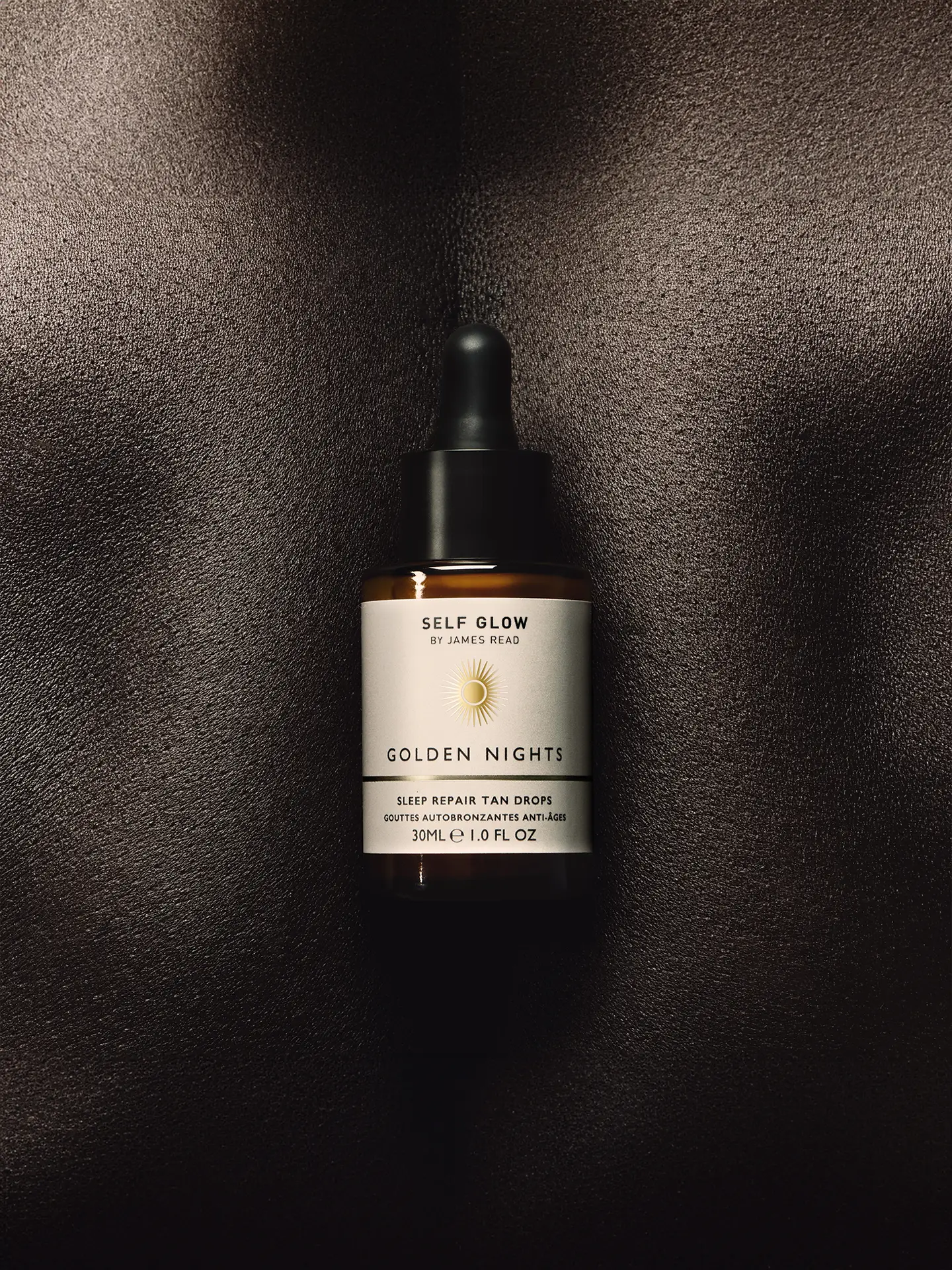 Self Glow by James Read ‘Golden Nights’ sleep tan drops bottle on a model’s back to create abstract skin texture background, art directed by Saltco
